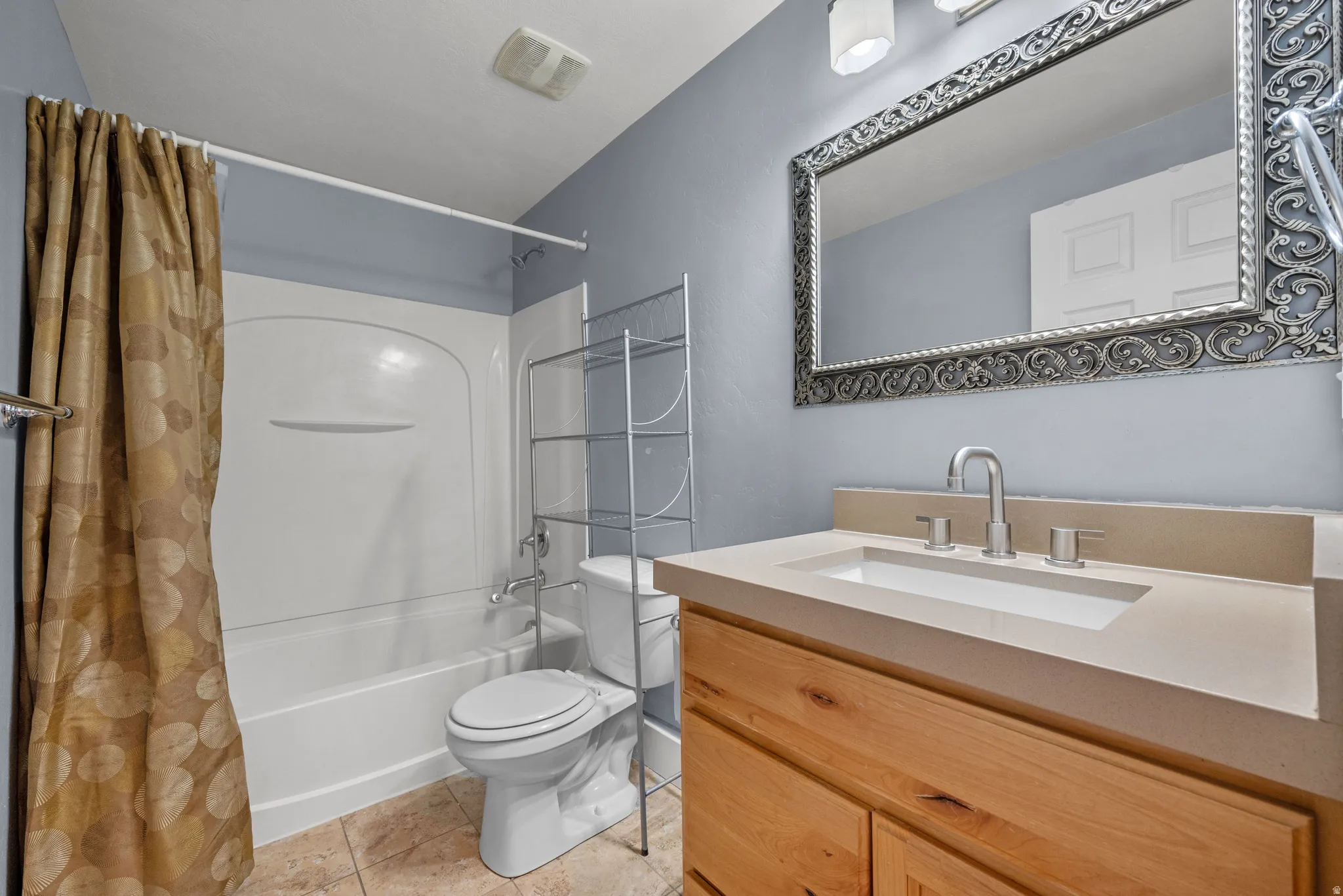 Bathroom featuring a light wood-finish vanity with a light-toned countertop and an integrated rectangular sink