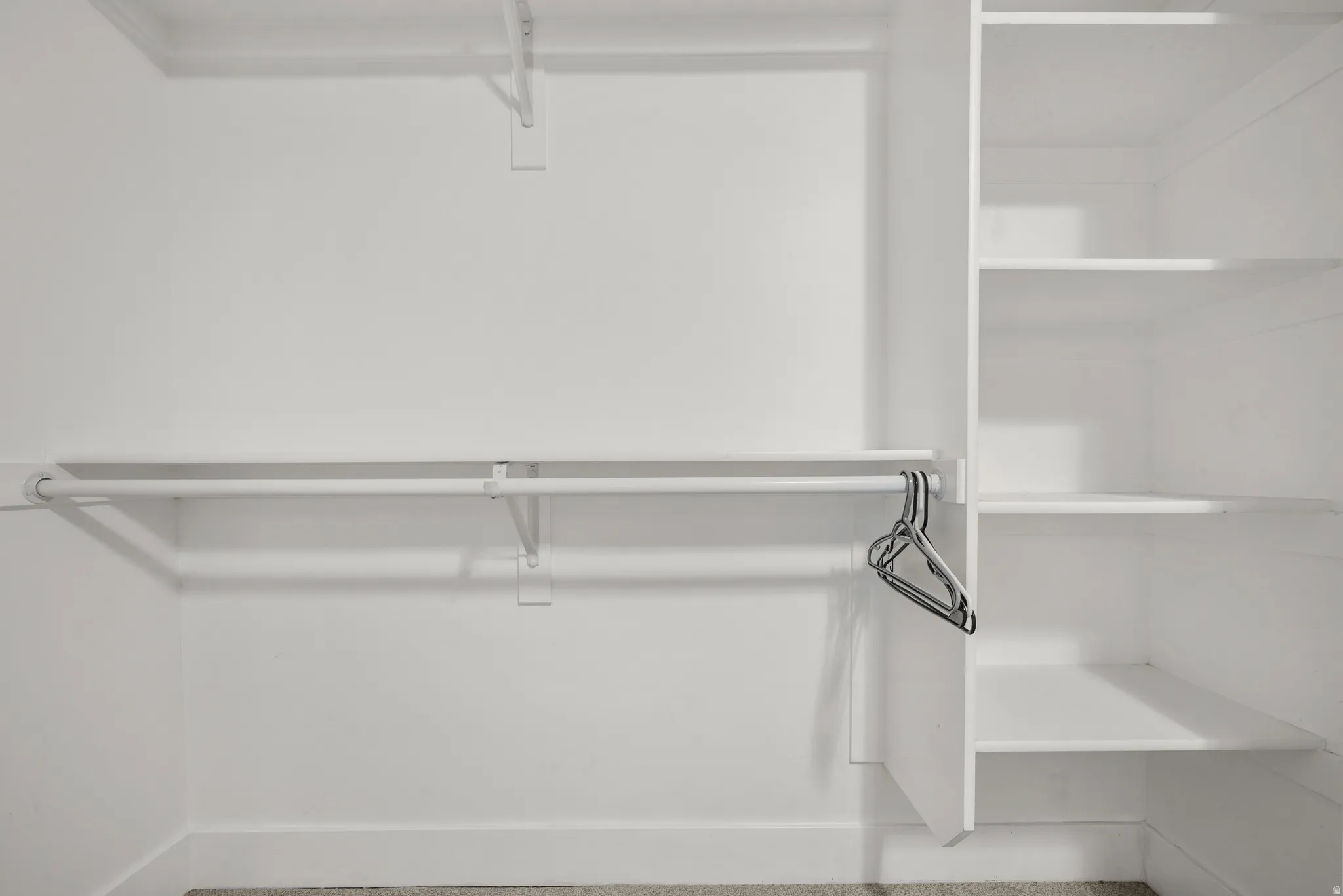 White closet system featuring multiple hanging rods and built-in shelving units
