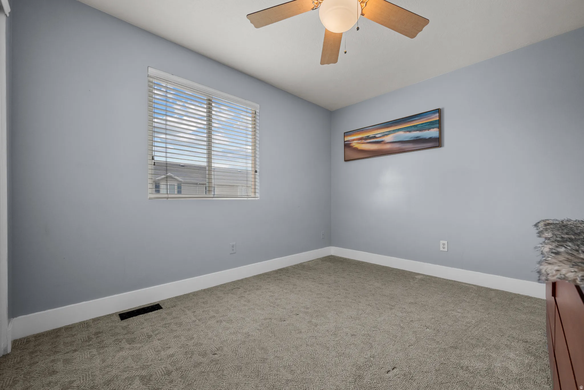 Room featuring a window with blinds, light blue walls, and grey patterned carpet
