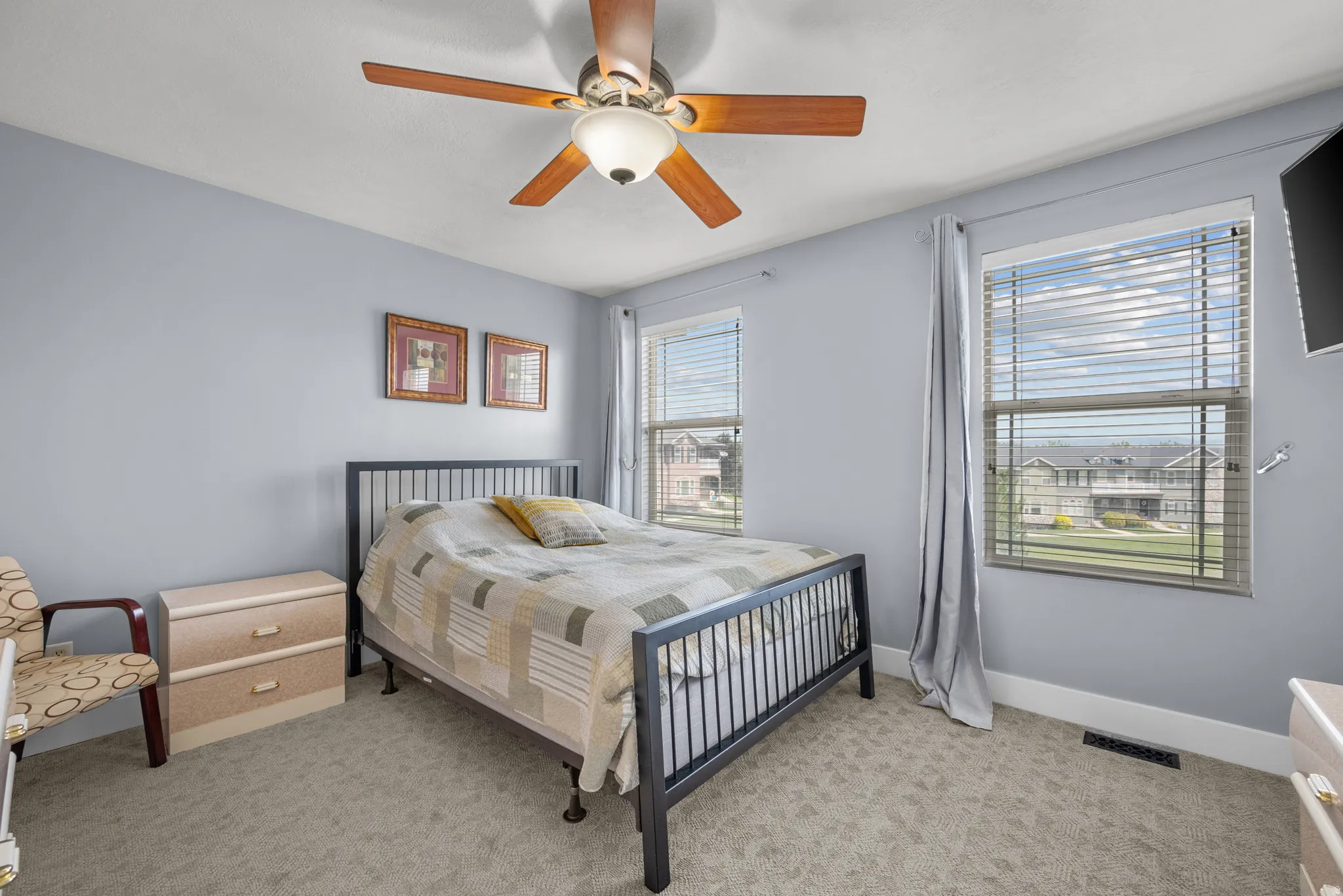 Carpeted room with a ceiling fan featuring wood-finish blades and an integrated light fixture
