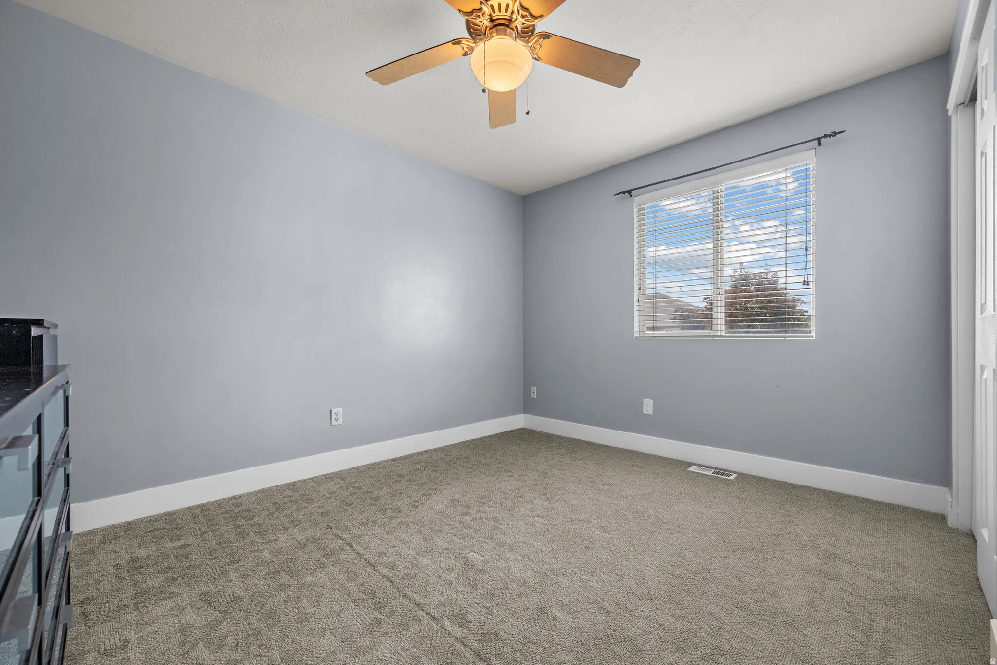 Carpeted room featuring a ceiling fan with integrated lighting, a window with horizontal blinds, and baseboard trim