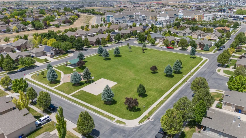Central green space featuring a manicured lawn, established trees, and paved perimeter pathways