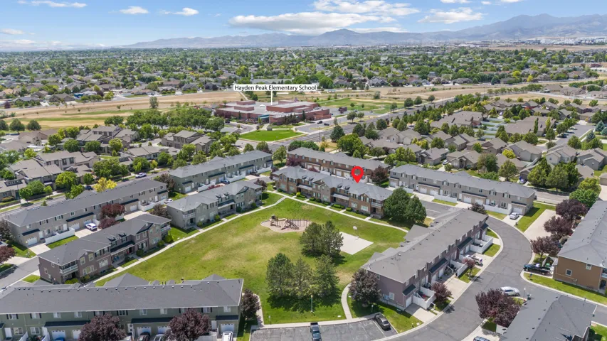 Aerial perspective showcasing a residential community with townhomes and detached houses, featuring green spaces and mature landscaping
