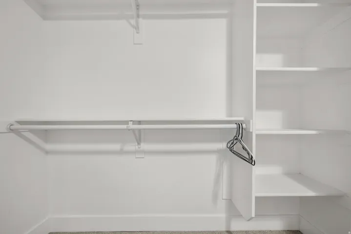 White closet system featuring multiple hanging rods and built-in shelving units