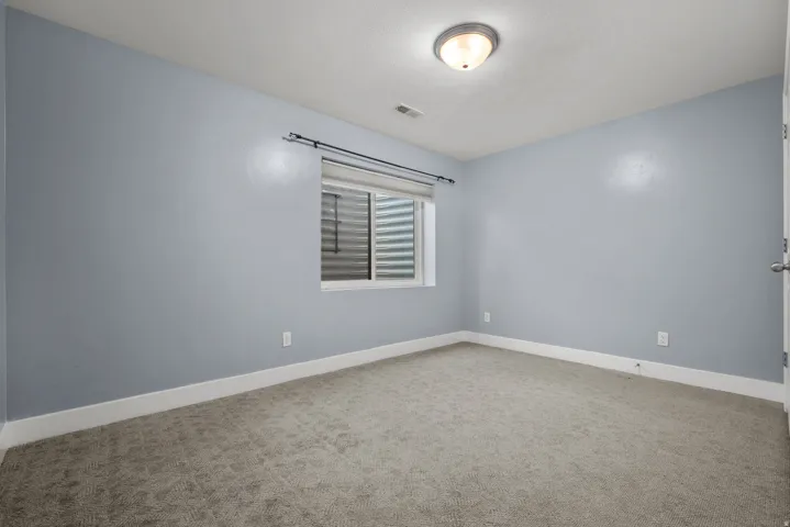 Carpeted room with a window featuring horizontal blinds, light blue walls, white baseboards, and a semi-flush mount ceiling light