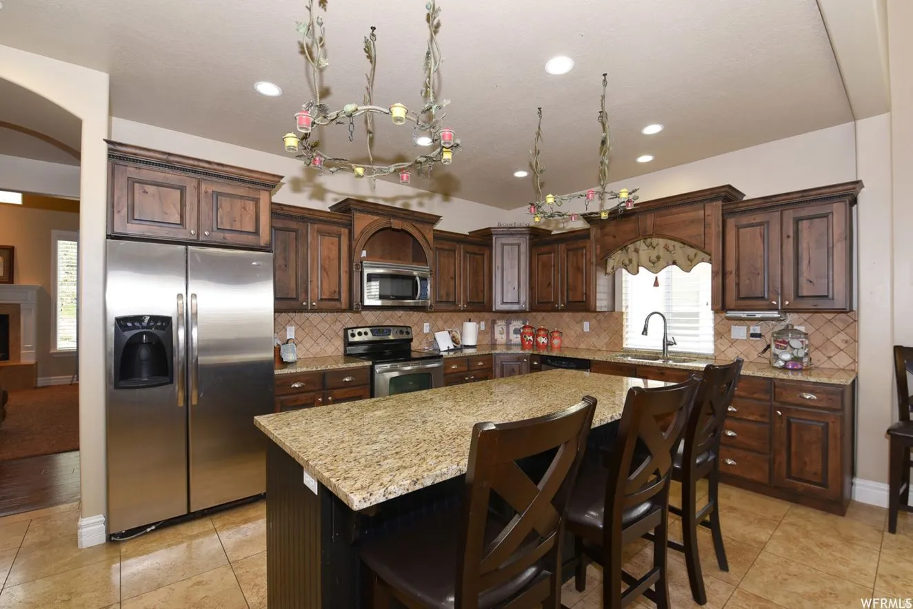 Kitchen featuring dark wood cabinetry, stainless steel appliances, granite countertops, and tile flooring