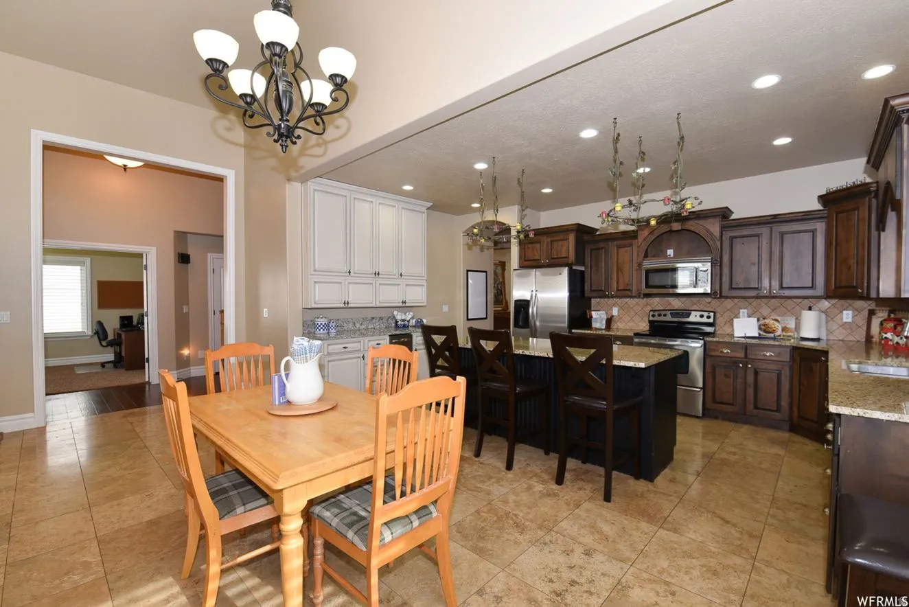 Kitchen featuring an island with stone countertop, dark wood cabinetry, stainless steel appliances, and tile flooring