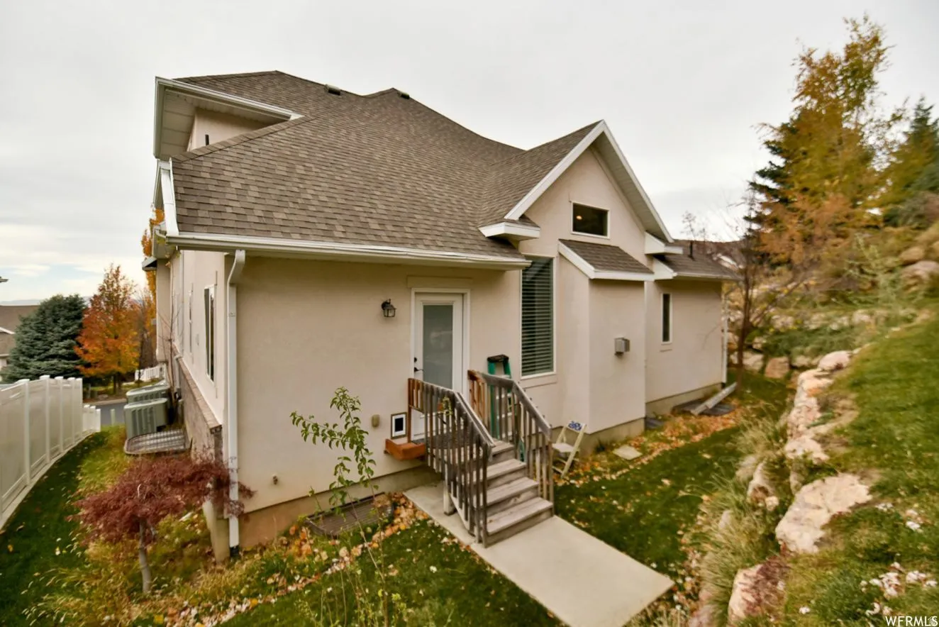 Rear exterior featuring stucco finish, a private entry with wood steps, and a concrete pathway