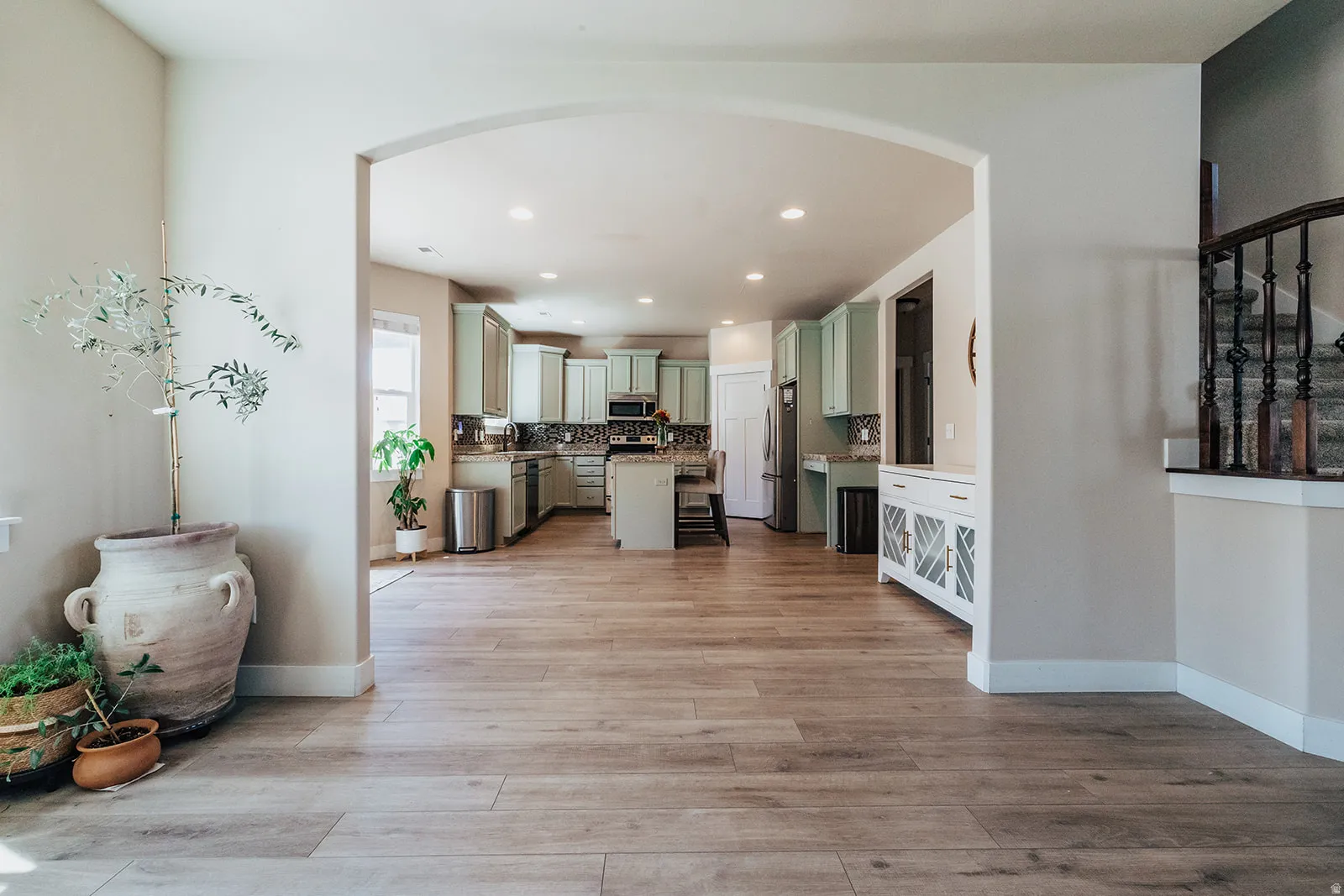 Open concept living space featuring wood-finish flooring throughout, an arched entryway, and recessed lighting
