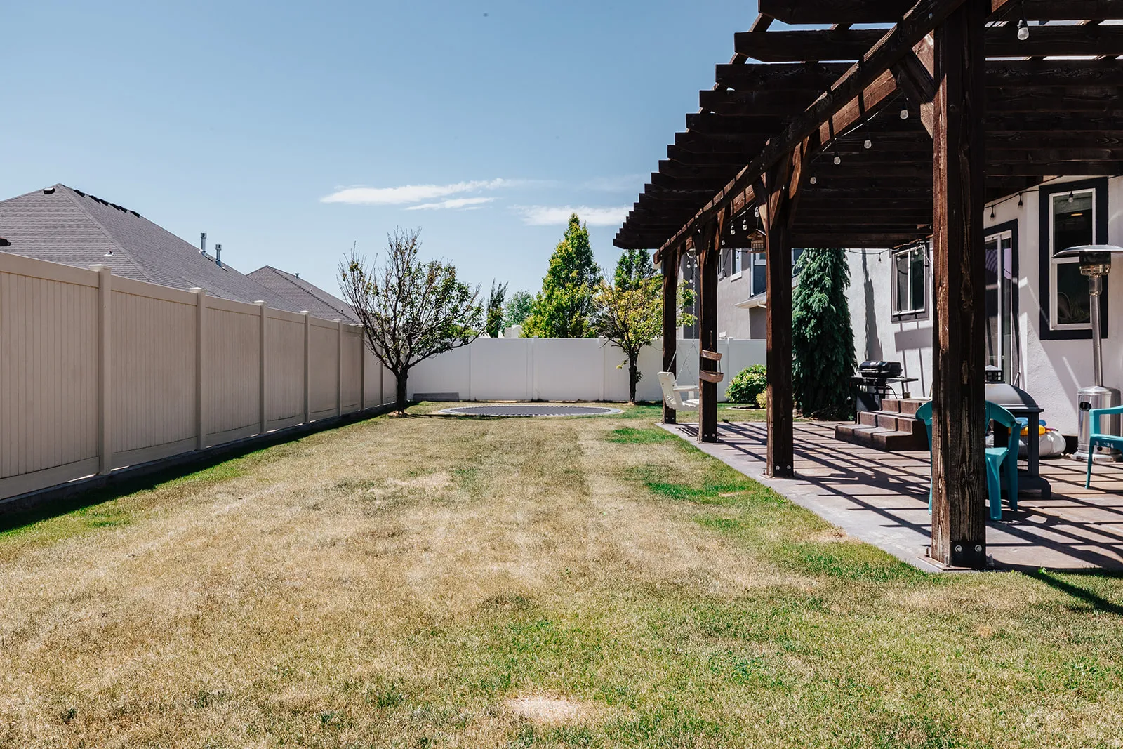 Expansive backyard with a wooden pergola-covered patio, paved patio flooring, and a privacy fence