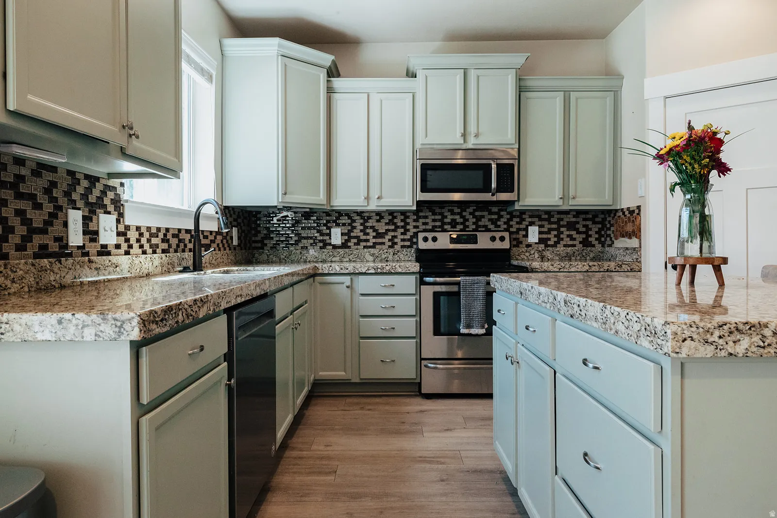 Kitchen featuring light-toned cabinetry, stainless steel appliances, and a mosaic tile backsplash