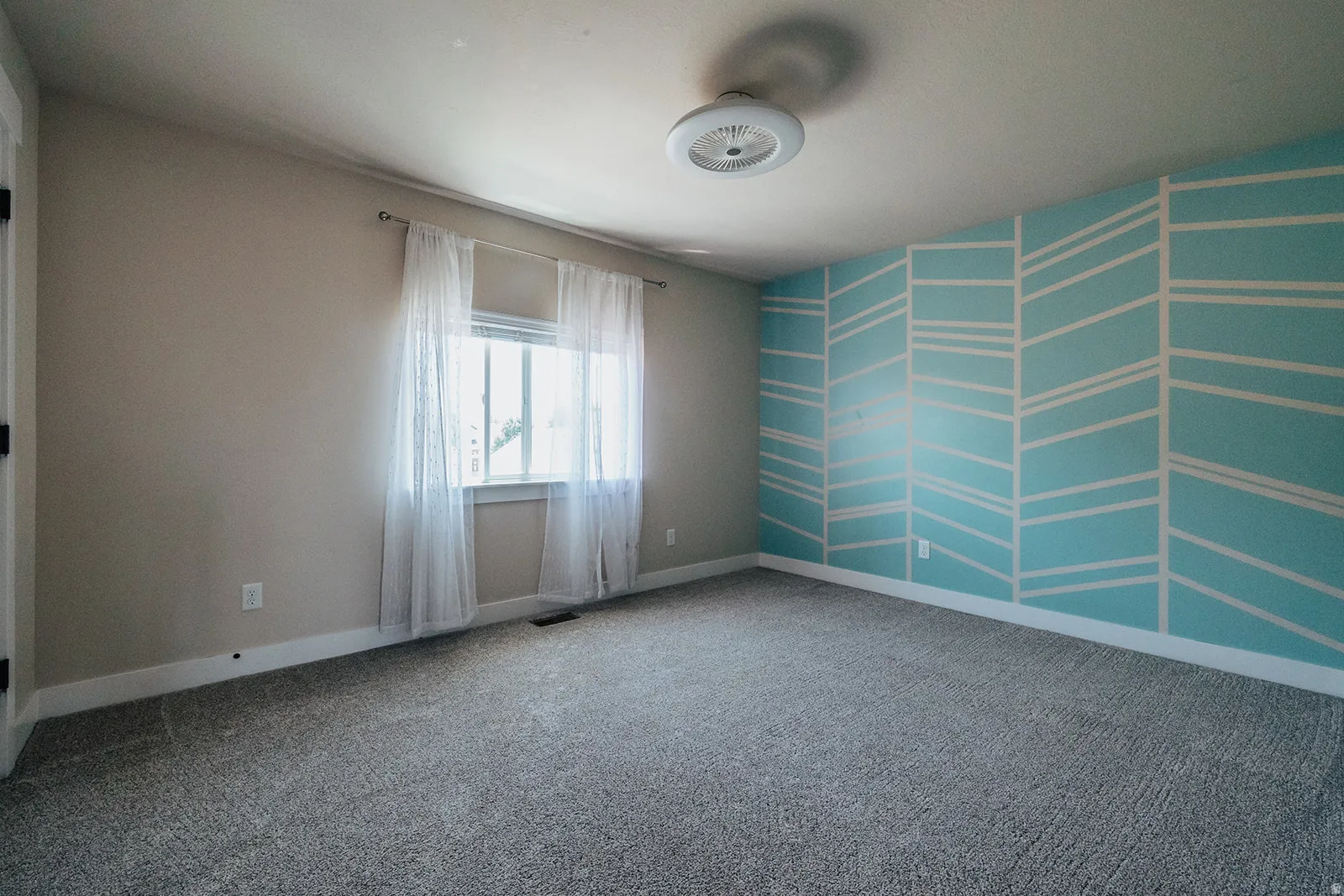 Bedroom featuring a window, patterned accent wall, neutral wall color, ceiling light fixture, and carpet flooring