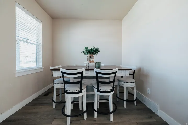 Recessed dining area featuring wood-finish flooring, a window with blinds, and light-toned walls