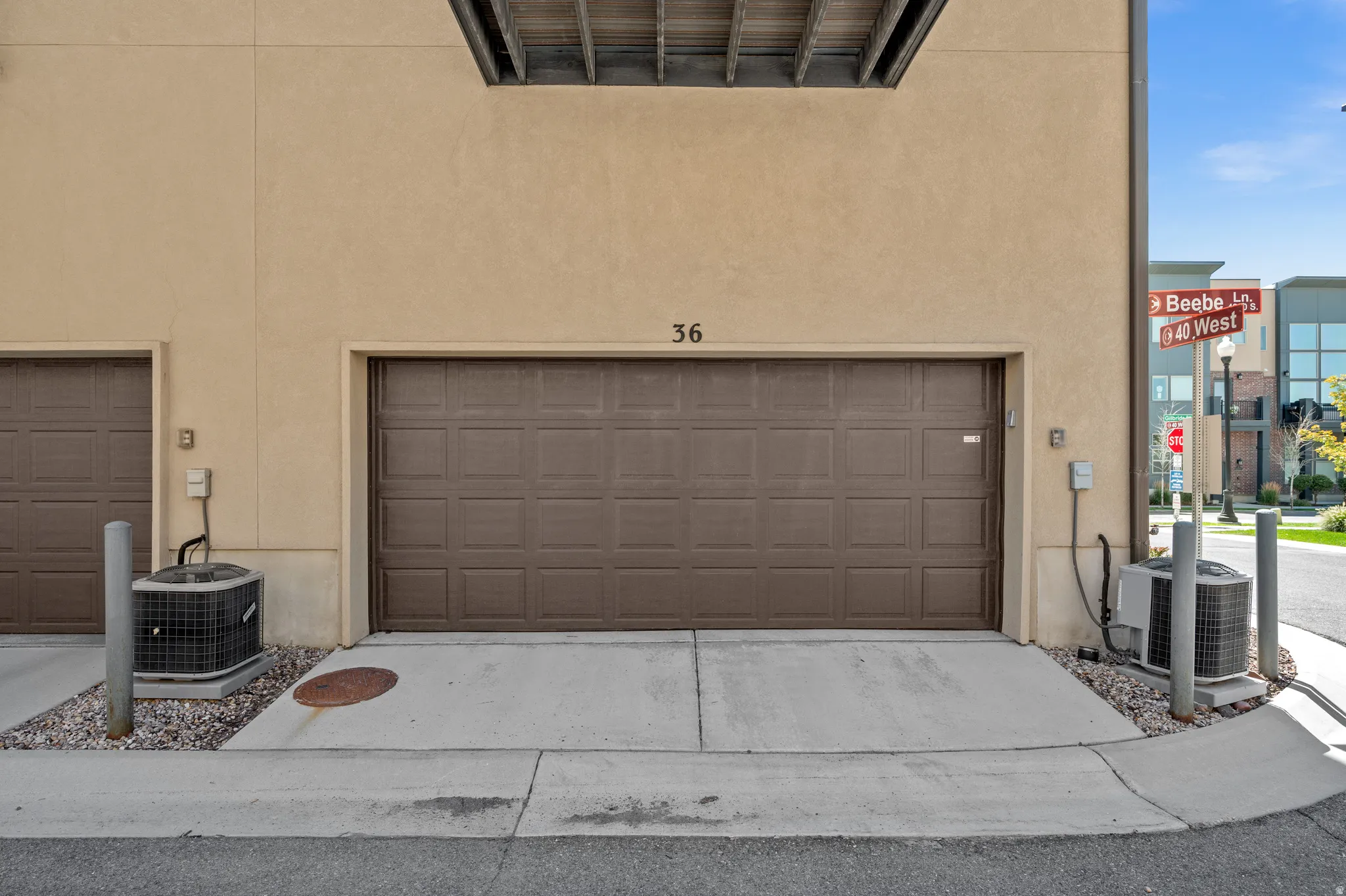 Stucco exterior with a brown panel garage door, concrete driveway, and exterior HVAC unit