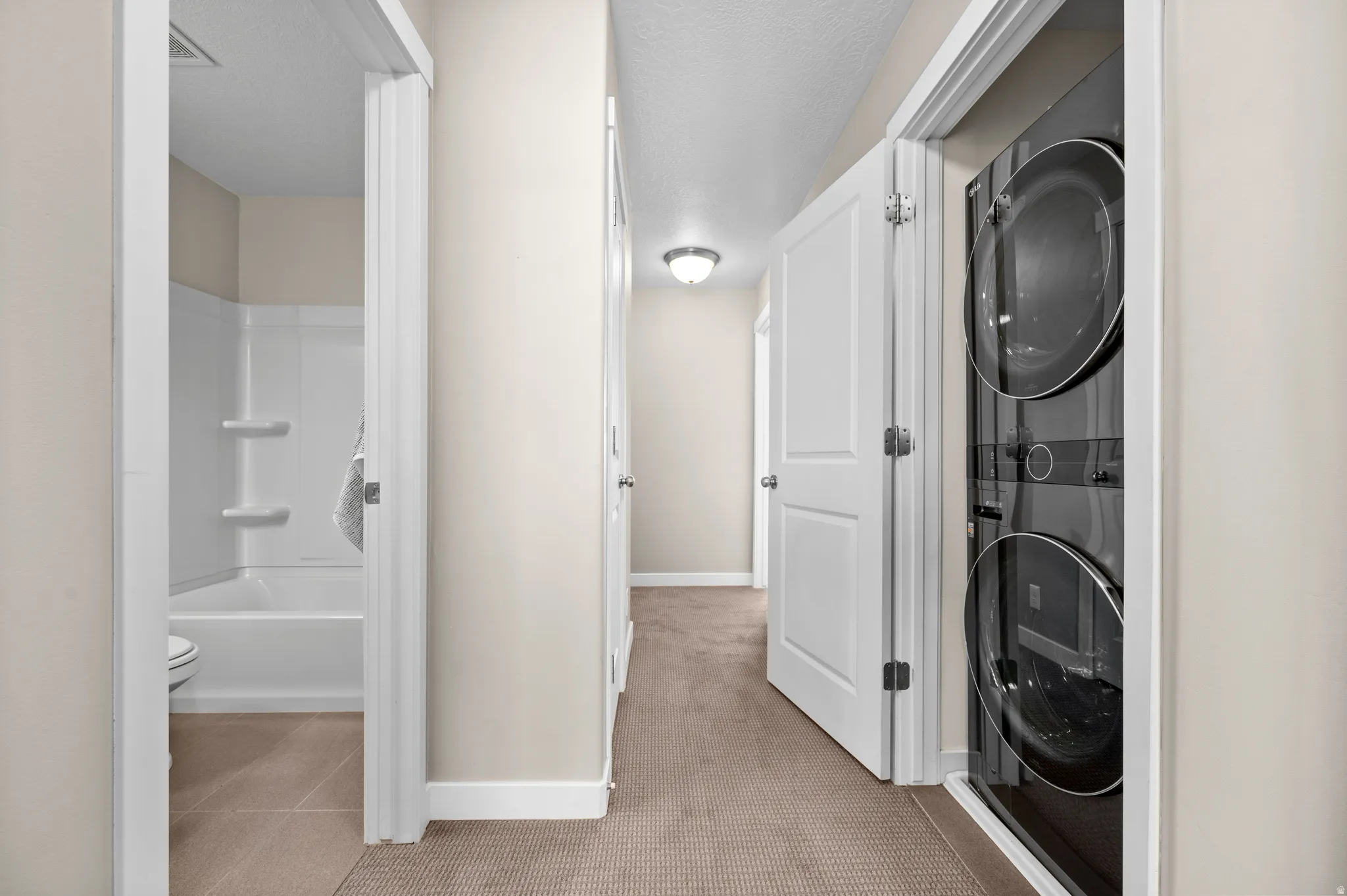 Hallway featuring warm neutral wall tones and carpeted flooring