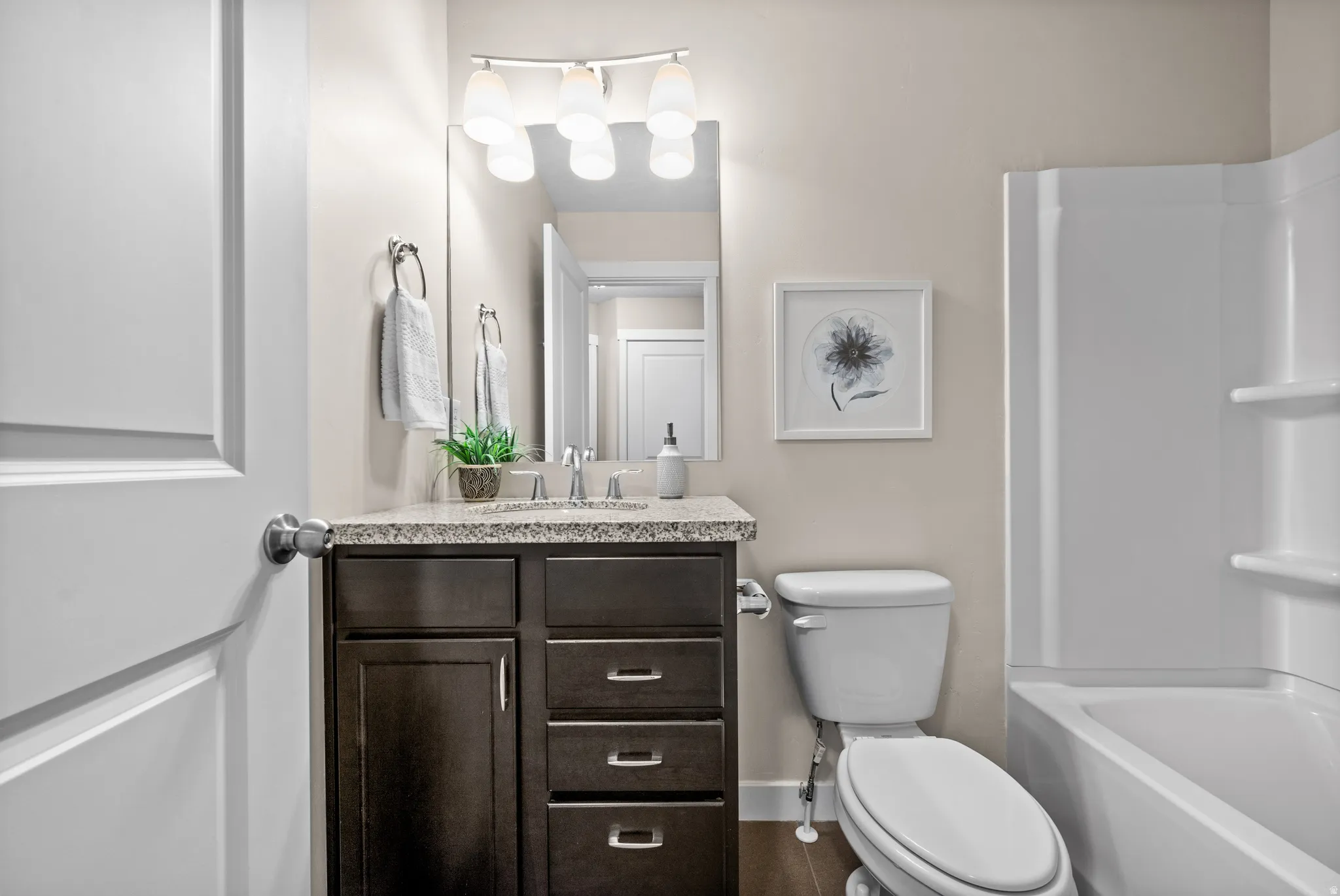 Bathroom vanity featuring a granite-style countertop, undermount sink, and dark wood-finish cabinetry with brushed nickel hardware