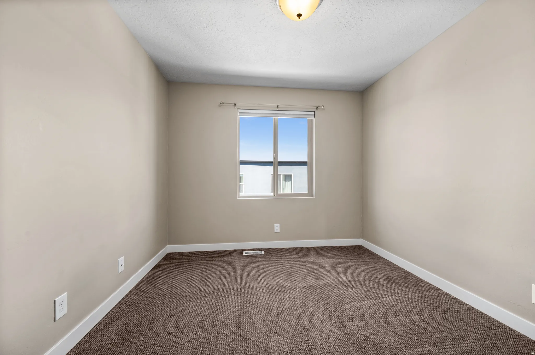 Neutral-toned interior with a single window, brown carpet flooring, and white trim