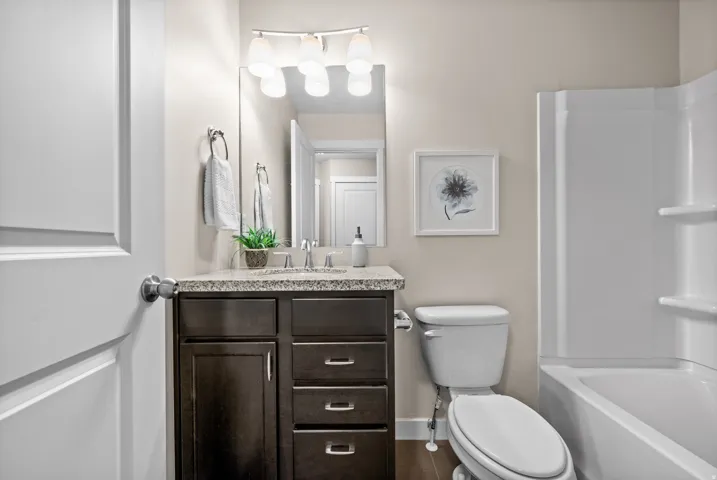 Bathroom vanity featuring a granite-style countertop, undermount sink, and dark wood-finish cabinetry with brushed nickel hardware