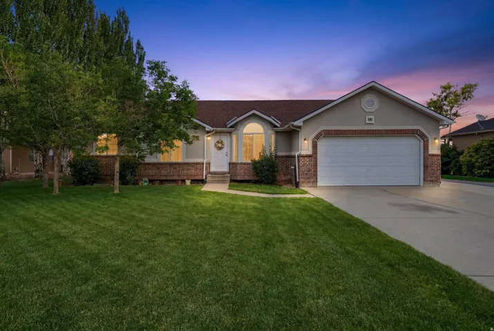Ranch-style exterior featuring a two-car garage, brick accents, and a front entry with an arched window