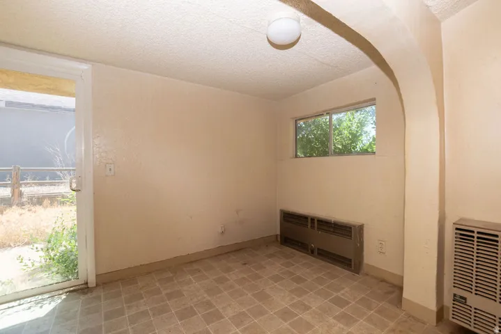 Room featuring a sliding glass door, a horizontal window, a permanent wall heater, a built-in floor heater, and a textured ceiling