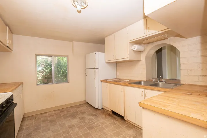 Kitchen featuring wood-finish countertops, upper and lower cabinetry, and a double basin sink