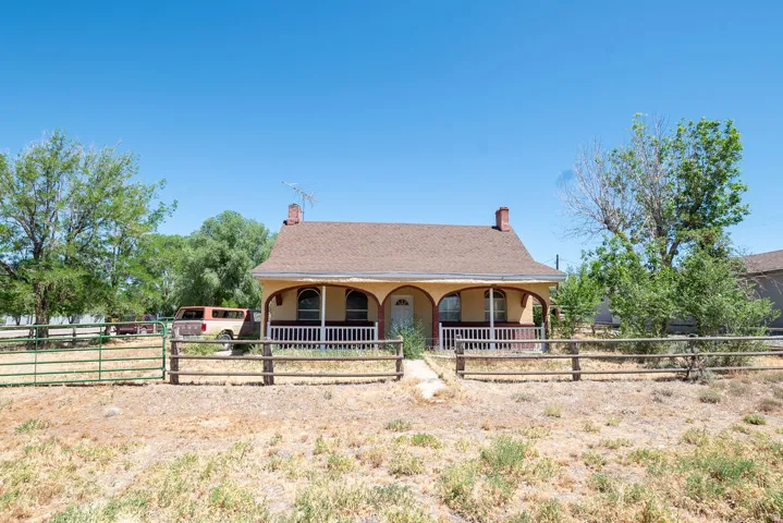 Single-story property featuring a covered front porch with white railings, arched window openings, and a brown shingle roof