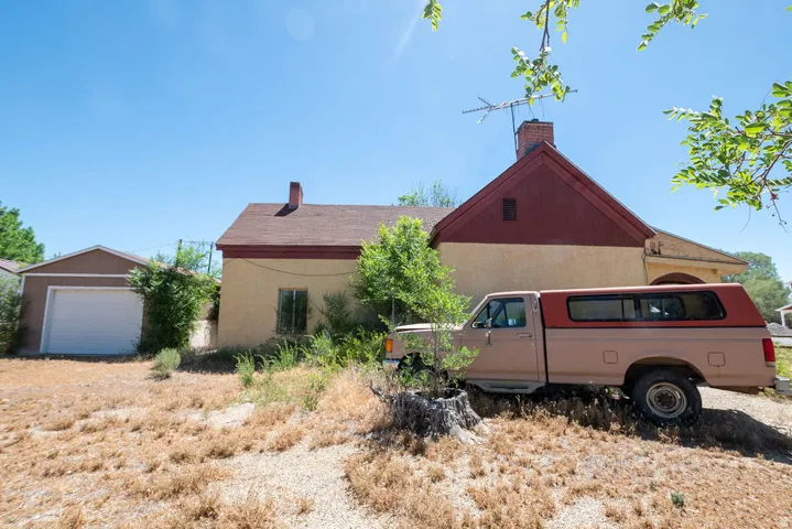 Exterior featuring a detached garage with a white overhead door, stucco siding, a brick chimney, and a gabled roofline