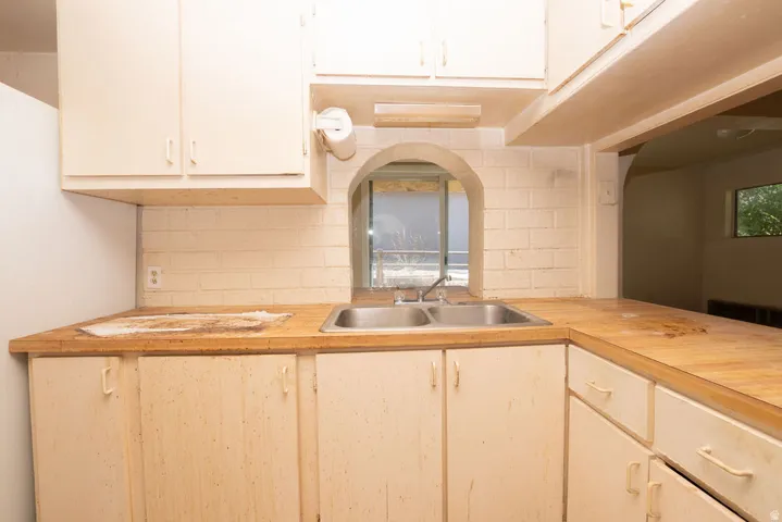Kitchen featuring dual stainless steel sink, wood-finish countertops, and white cabinetry