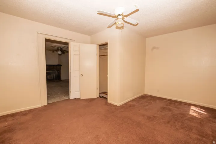 Bedroom featuring a ceiling fan with light fixture, neutral wall paint, and brown carpet flooring