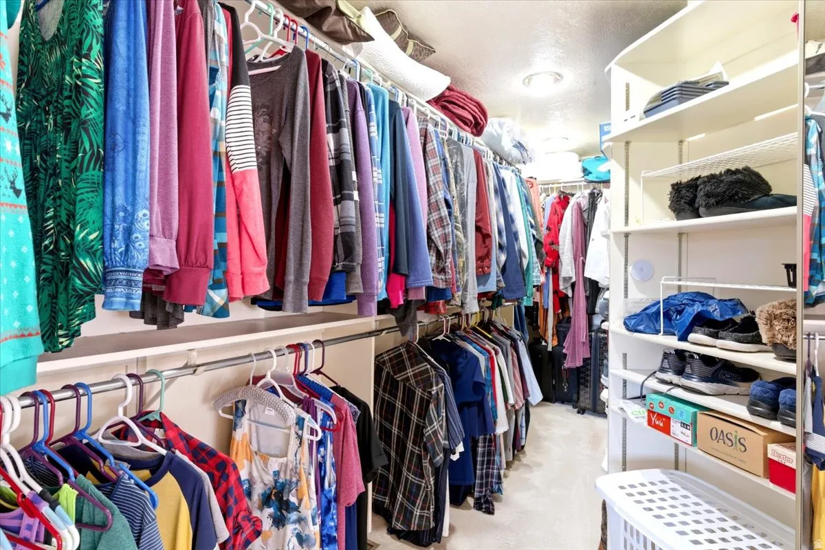 Expansive walk-in closet featuring built-in shelving, multiple hanging rods, and recessed lighting