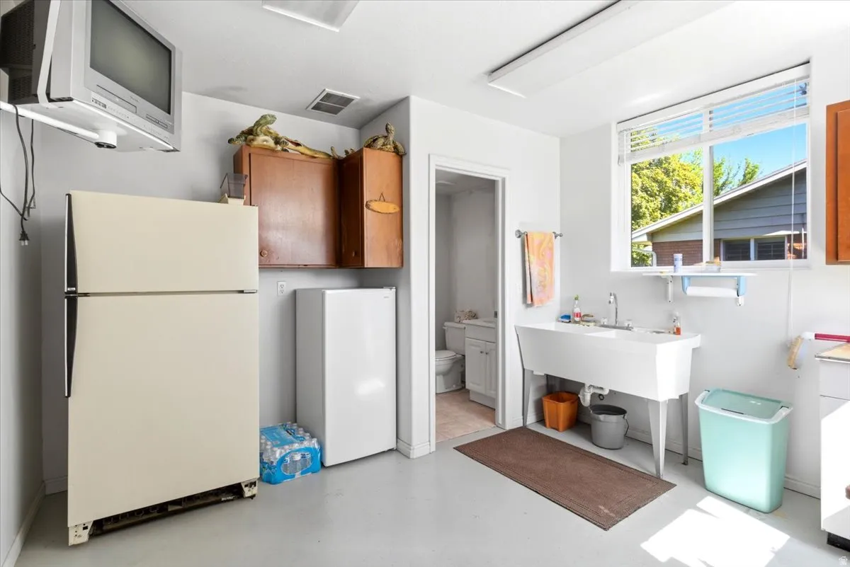 Dedicated utility space featuring a large single-basin sink, light wood-finish cabinetry, and a bright window