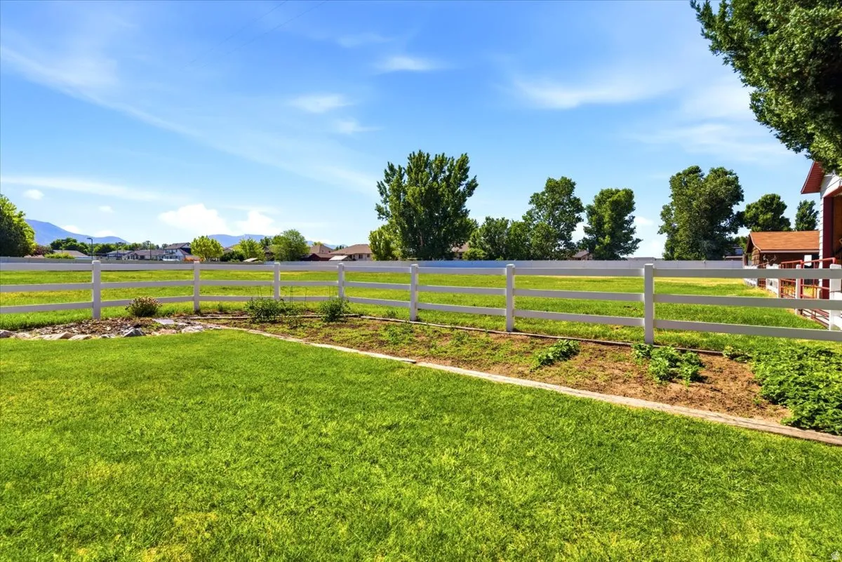 Expansive green lawn bounded by a white three-rail fence
