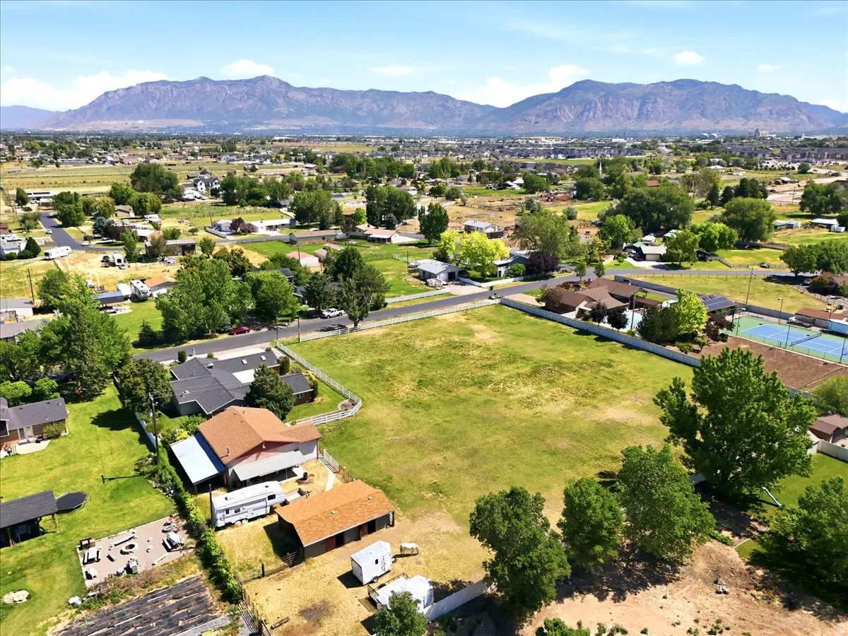 Expansive grassy lot with surrounding mature trees and mountain scenery