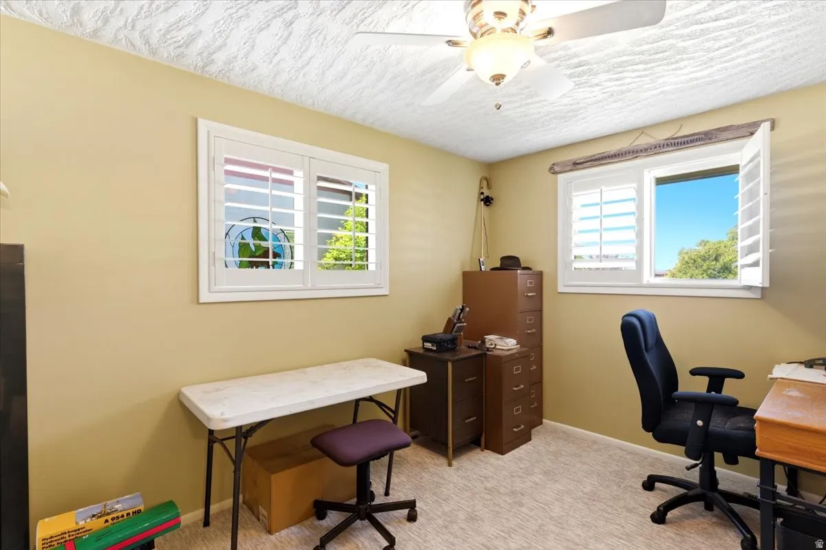 Room featuring two windows with white plantation shutters, neutral-toned walls, and a textured ceiling with a ceiling fan