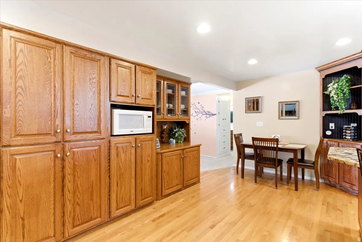 Kitchen with extensive wood cabinetry, an integrated microwave, and wood-finish flooring