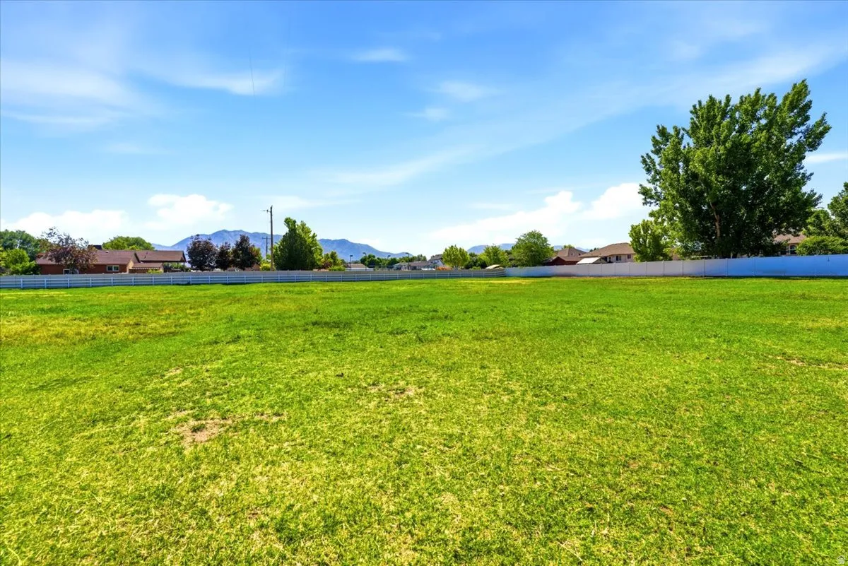 Expansive green space featuring a clear sky, distant mountains, and a perimeter fence