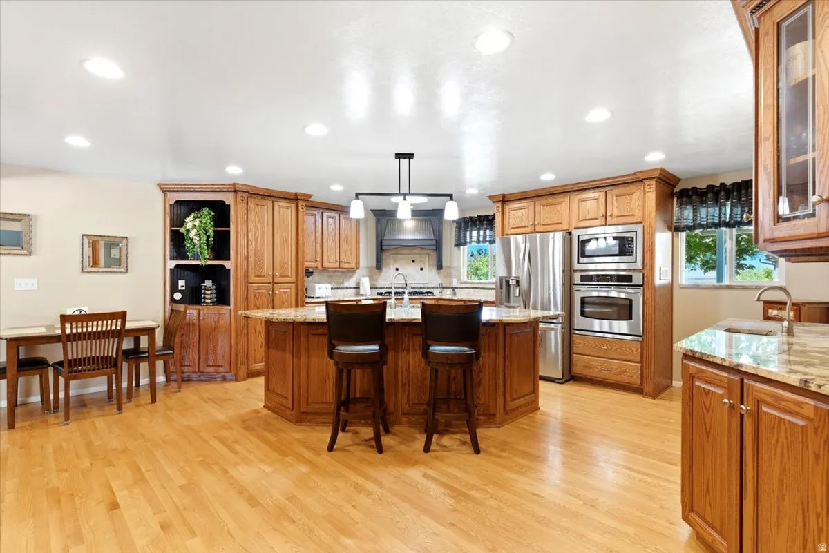 Spacious kitchen featuring wood-finish flooring, recessed lighting, and a large central island with seating