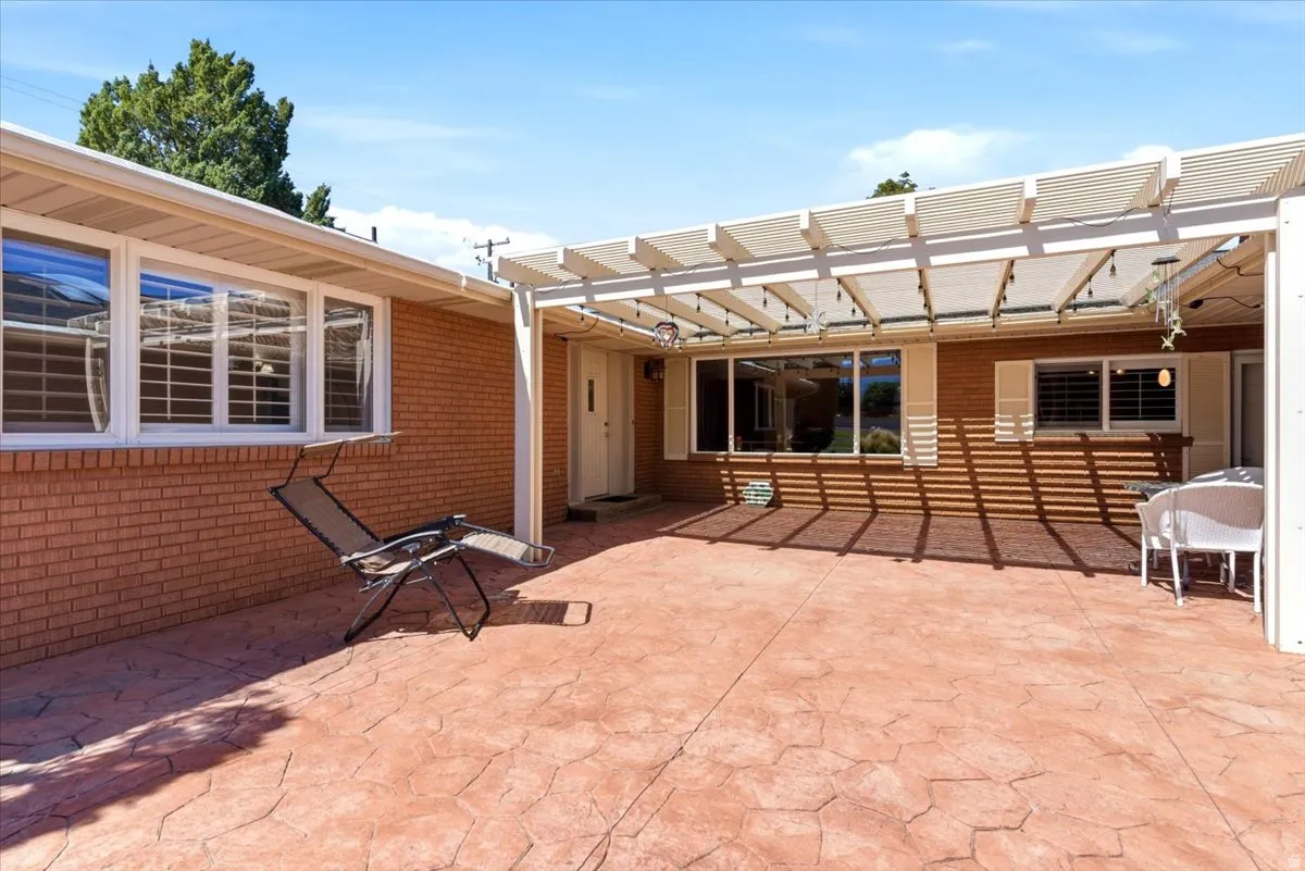 Expansive stamped concrete patio featuring a white slatted pergola