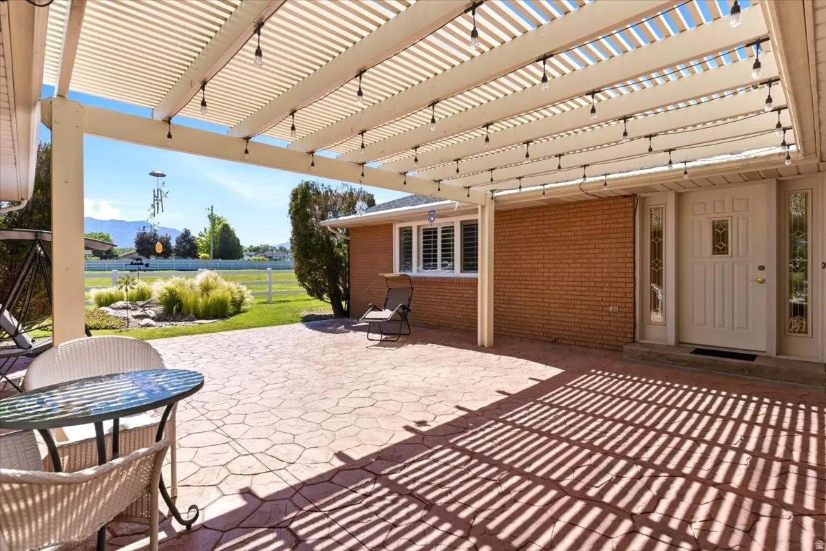 Expansive stamped concrete patio with overhead pergola featuring integrated string lighting