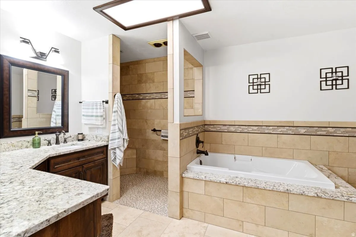 Bathroom featuring a built-in soaking tub and a walk-in shower with pebble tile flooring