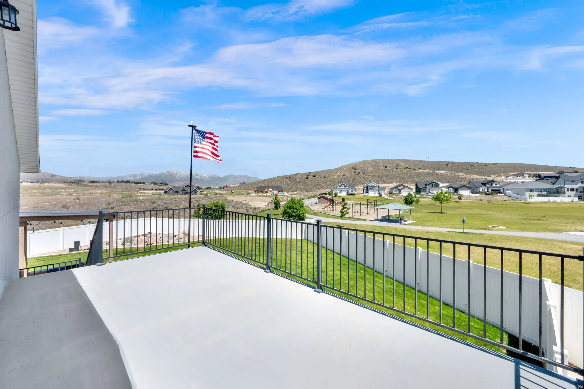 Exterior deck with a black metal railing and a distant mountainous backdrop