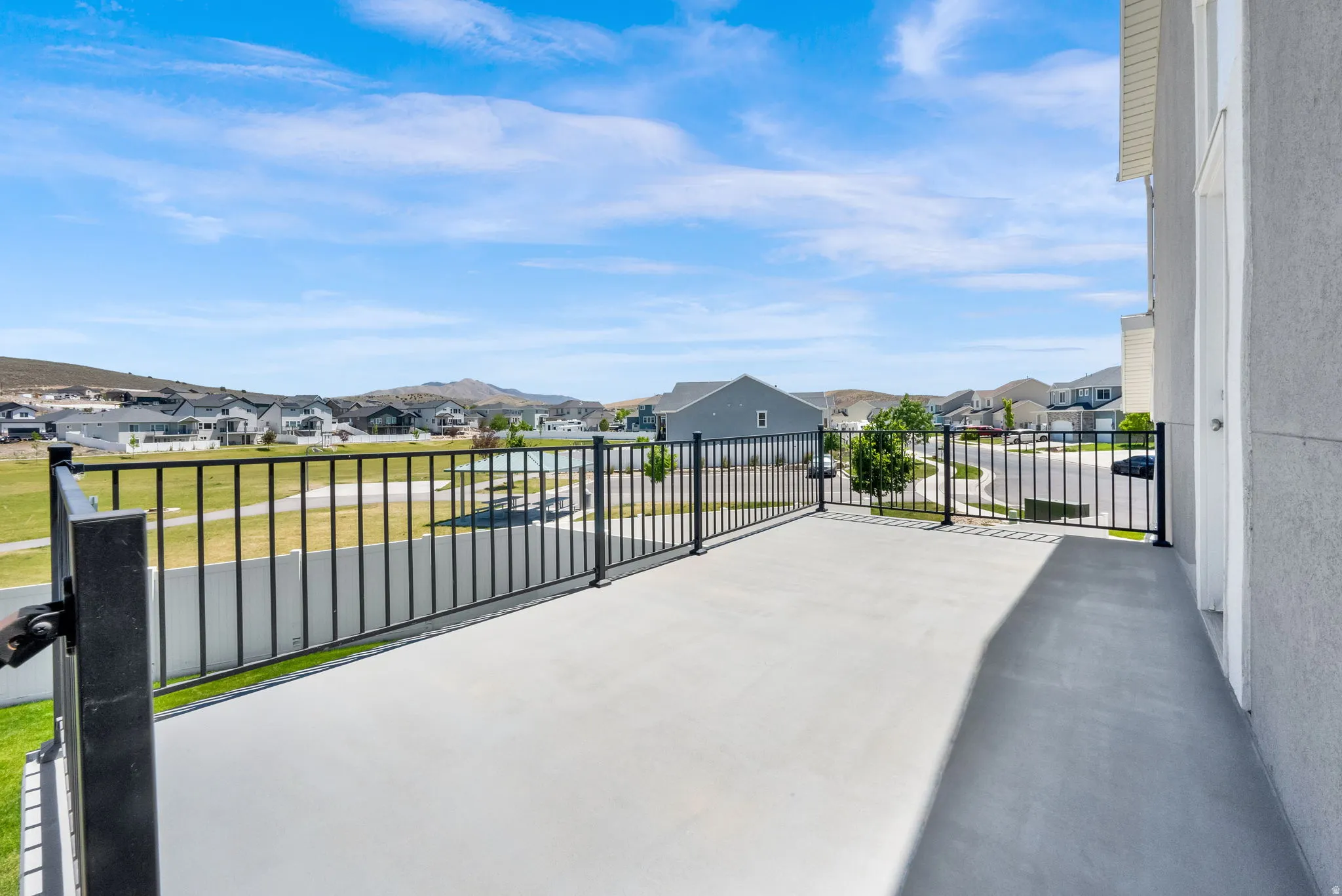 Spacious upper-level deck featuring a concrete surface and black metal railings