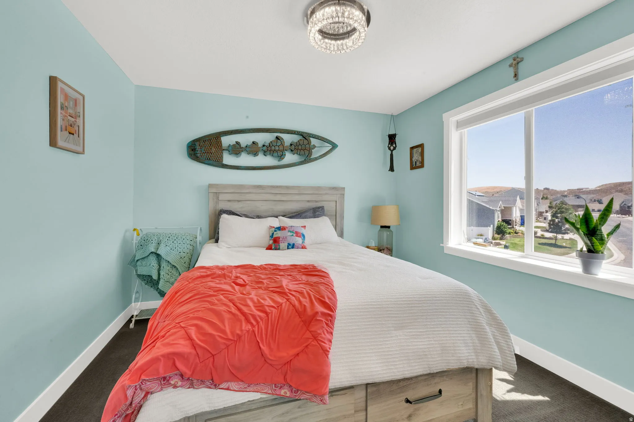 Bedroom featuring light blue walls, dark carpet flooring, and a large window with white trim