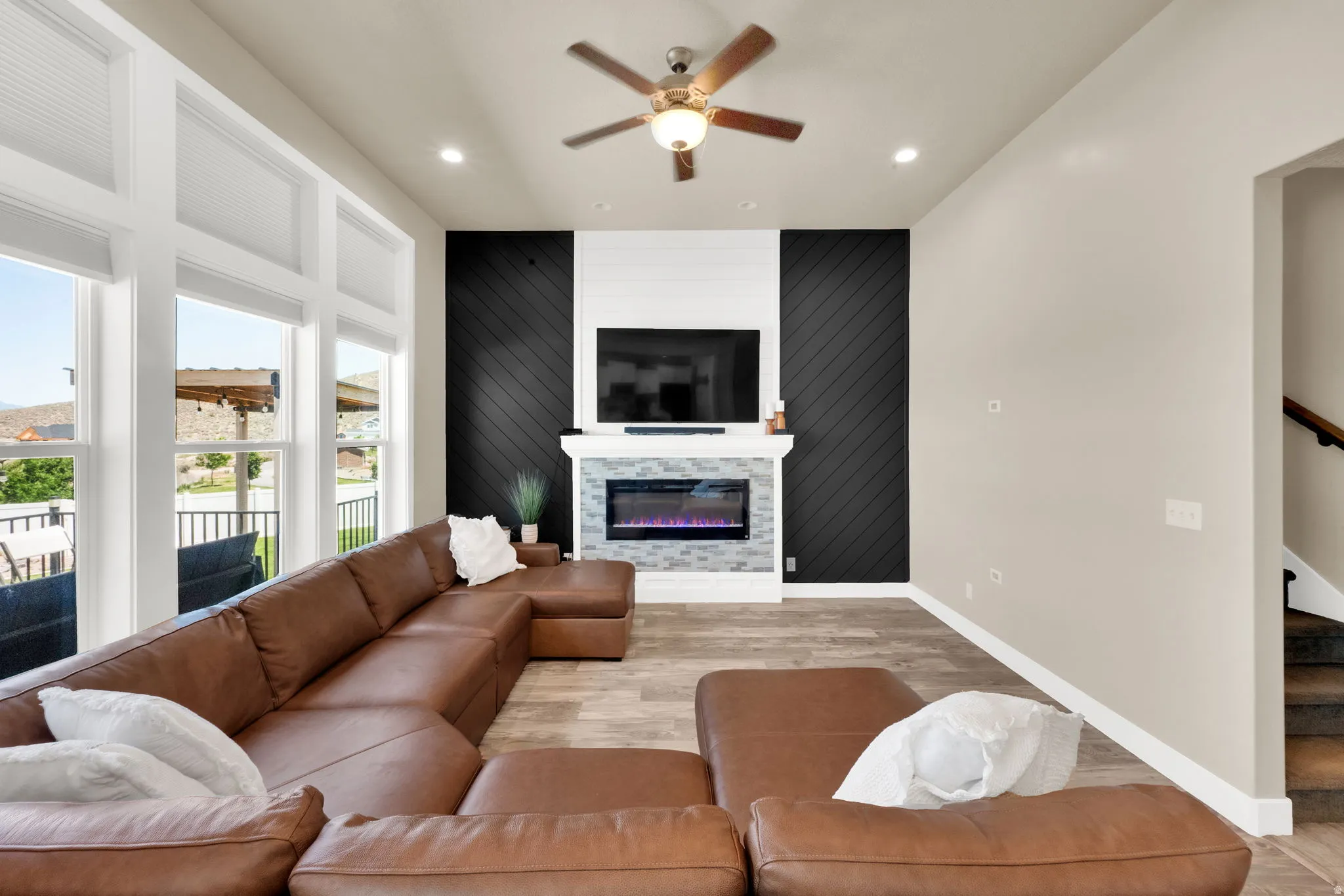 Living area featuring an electric fireplace with a stone tile surround and white mantel, flanked by accent walls with diagonal wood paneling