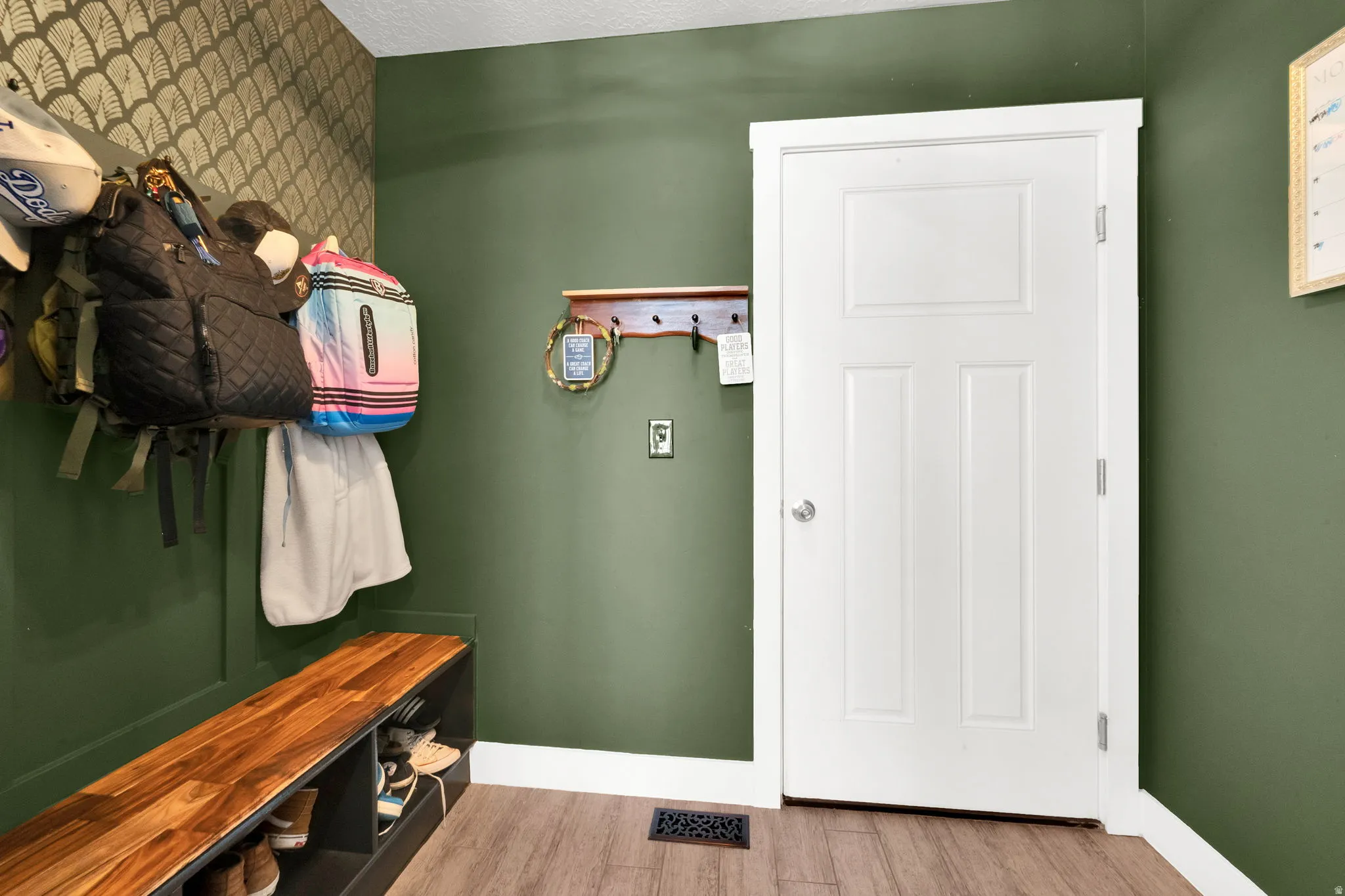 Entryway featuring wood-finish flooring and a solid panel door with white trim
