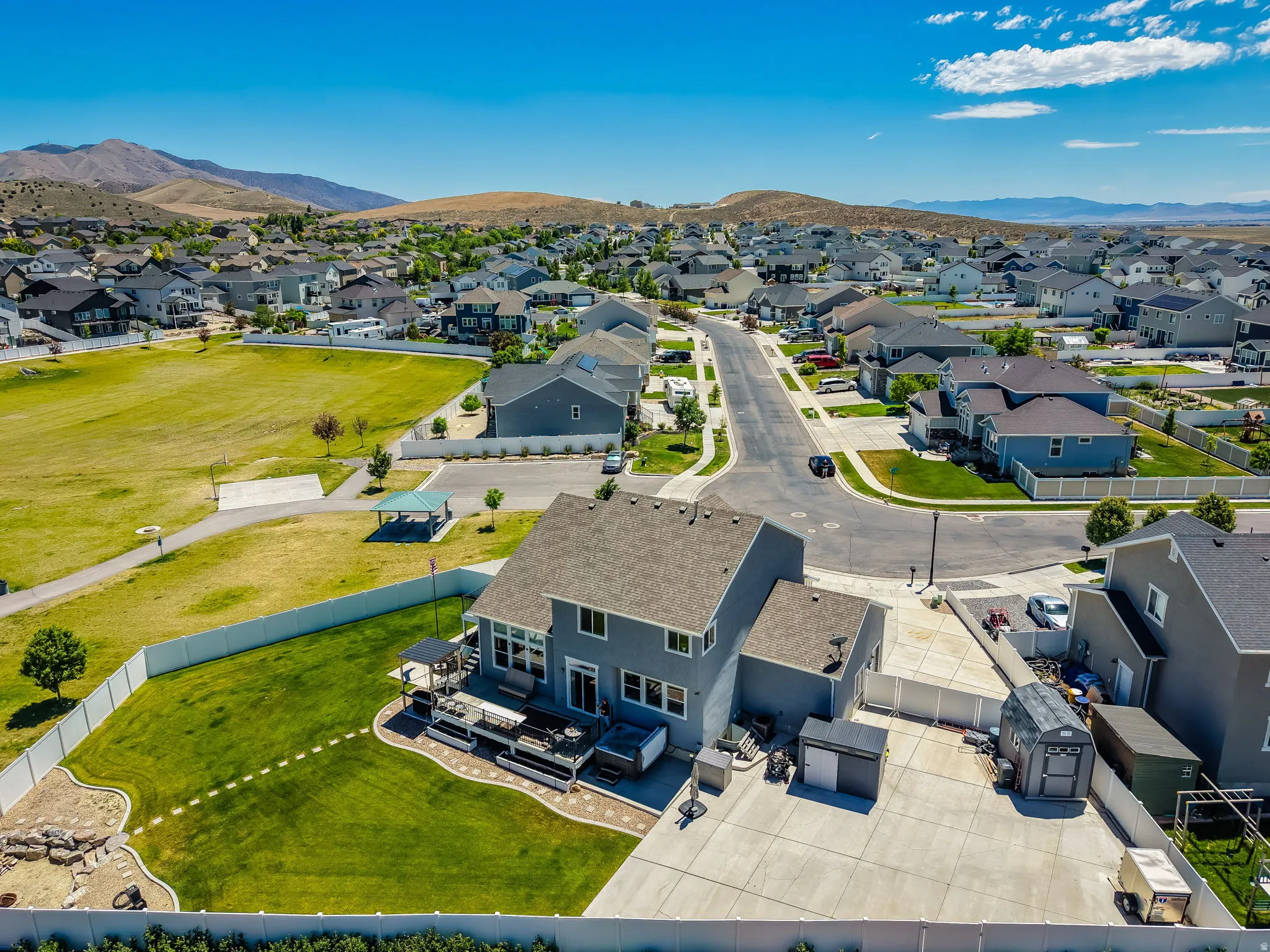 Expansive backyard featuring a manicured lawn, a multi-level deck, and a white perimeter fence