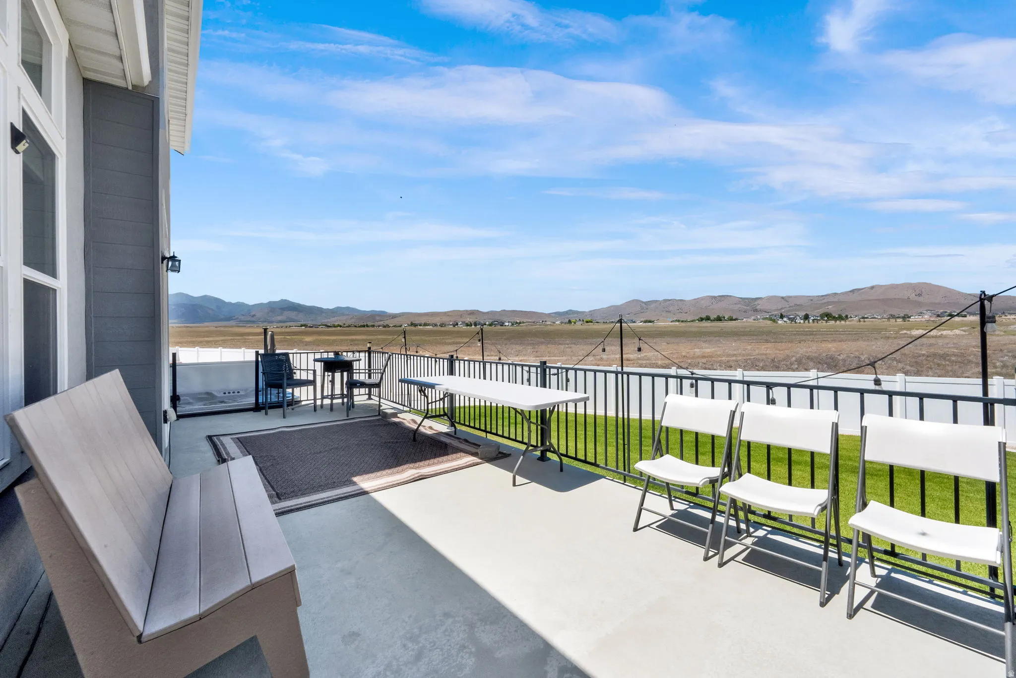 Expansive concrete patio featuring a black metal railing and a backdrop of distant hills