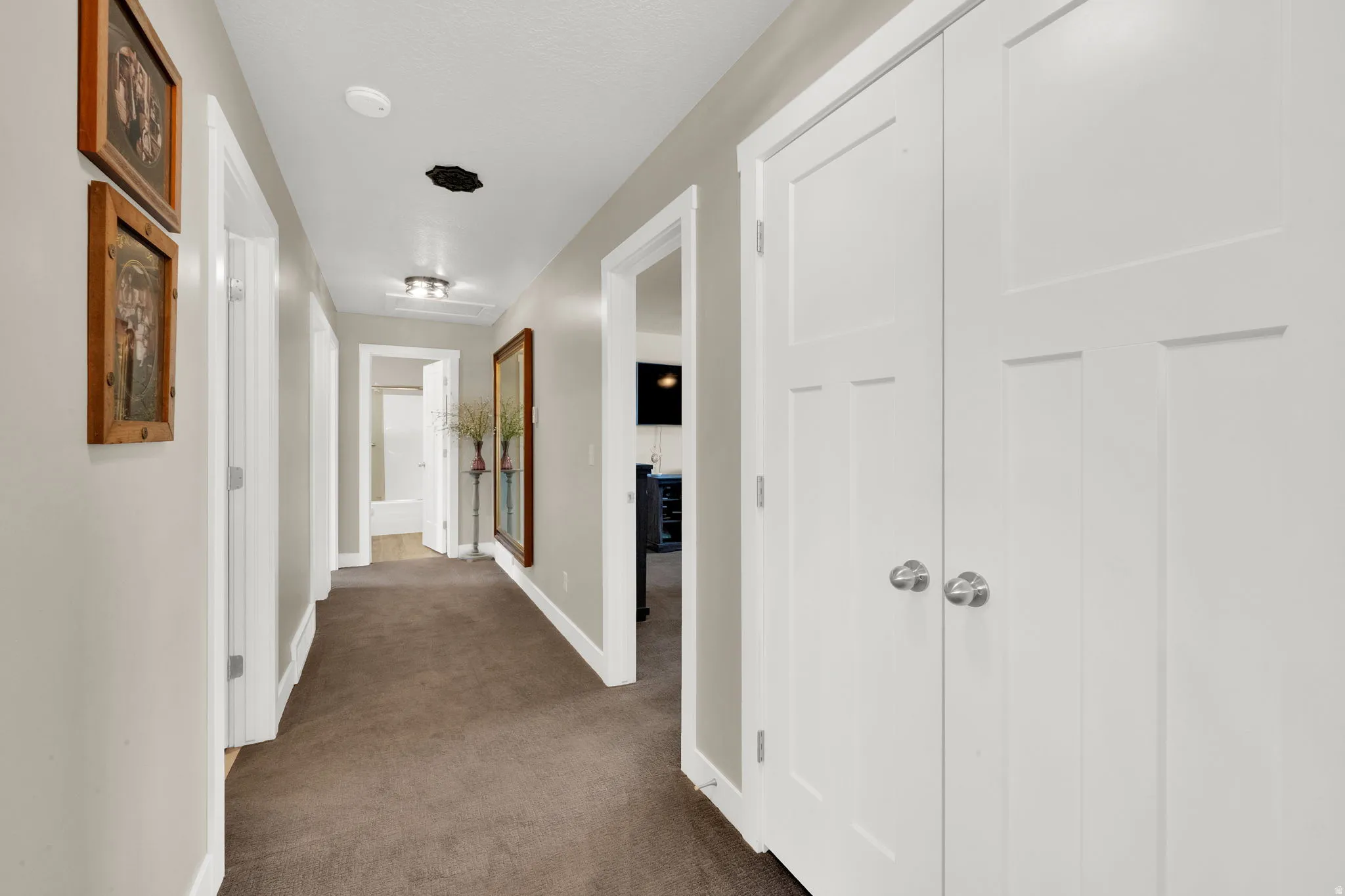 Hallway featuring neutral wall tones, white trim, and a textured carpet