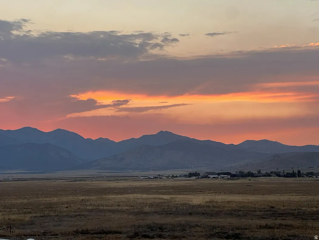 Expansive open landscape with distant mountains under a vibrant sunset sky