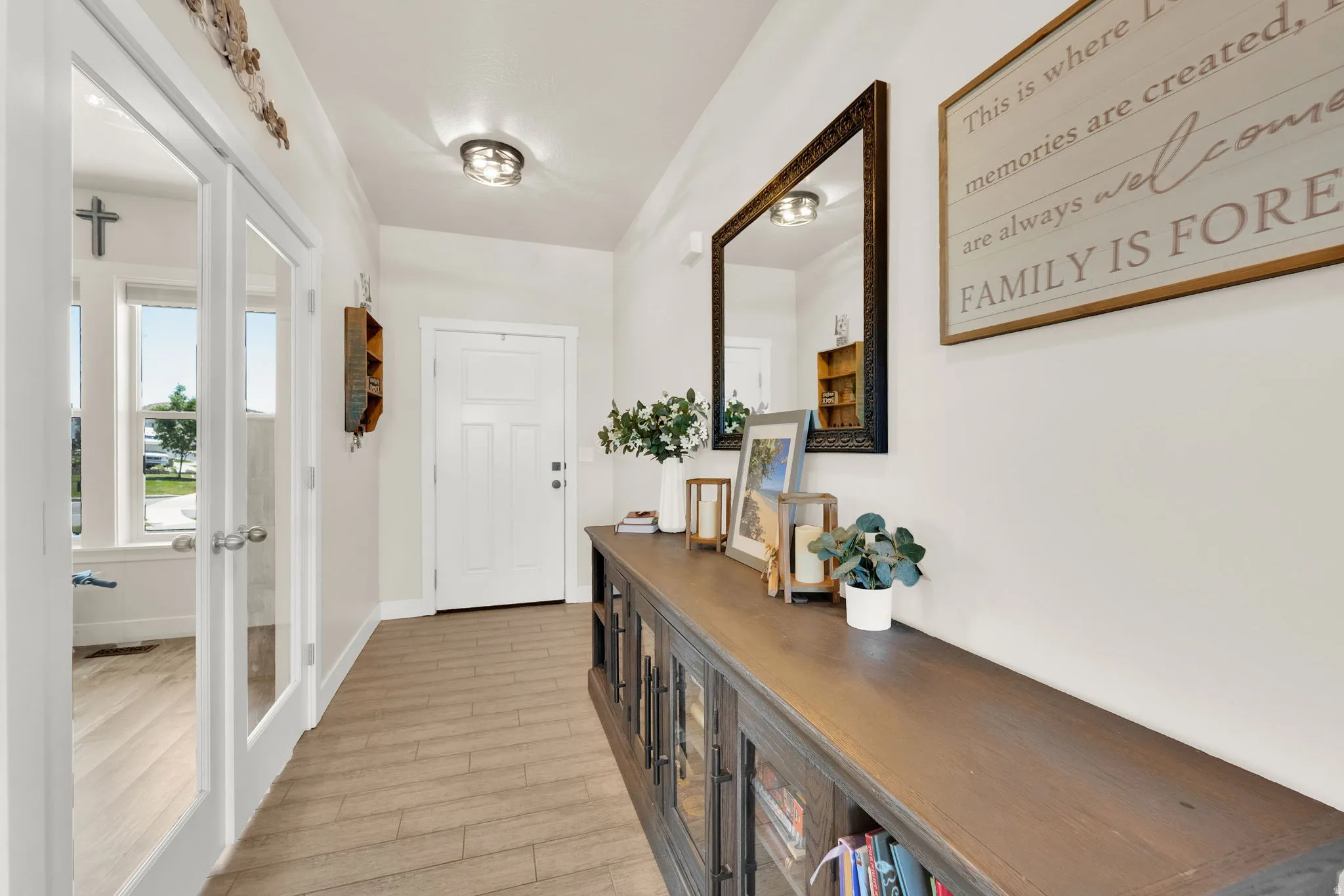 Entryway featuring wood-finish flooring, a white paneled entry door, and a built-in console cabinet with glass-front doors